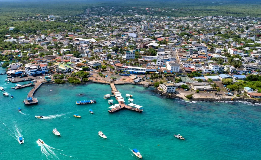 Aerial view of Puerto Ayora on Santa Cruz Island, showing the urban area, waterfront, docks, and surrounding protected landscape in Galápagos.