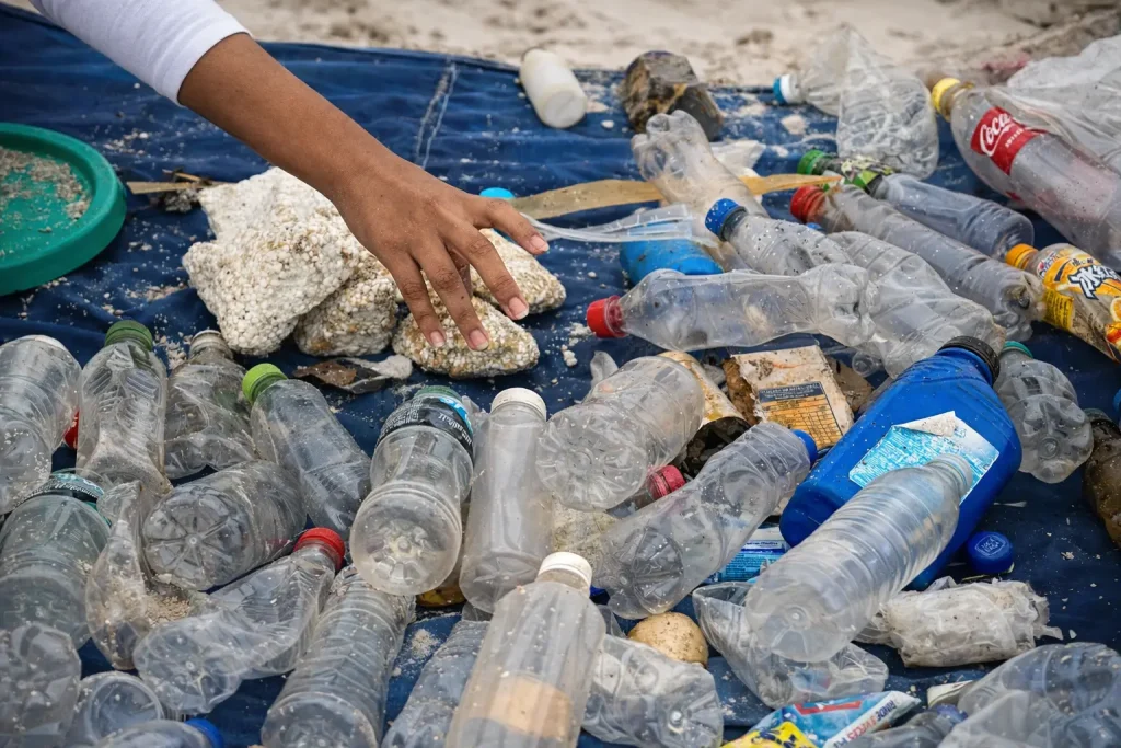 Plastic bottles, foam debris, and other waste collected from a Galápagos beach are spread across a blue tarp during a coastal cleanup.
